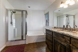 Bathroom featuring vanity, a bath, a stall shower, and dark tile patterned floors
