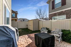 Fenced backyard with a patio, a storage shed, and area for grilling