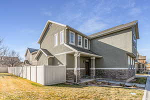 View of home's exterior with stucco siding, stone siding, and roof with shingles