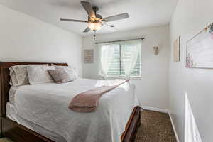 Carpeted bedroom with baseboards and a ceiling fan