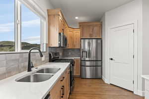 Kitchen featuring stainless steel appliances, backsplash, light wood-type flooring, light stone counters, and recessed lighting