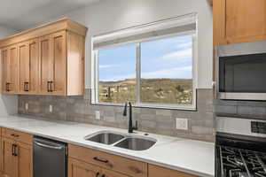 Kitchen featuring stainless steel appliances, backsplash, light wood finish cabinets, light stone counters, and a mountain view