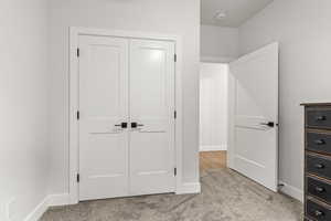 Unfurnished bedroom featuring a closet and light colored carpet
