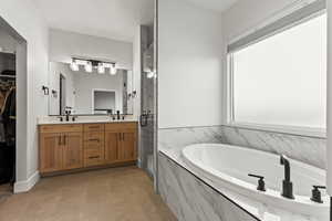 Bathroom featuring a marble finish shower, a bath, double vanity, and a walk in closet