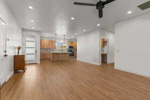 Kitchen featuring decorative light fixtures, open floor plan, a center island, light countertops, and wood finish cabinetry
