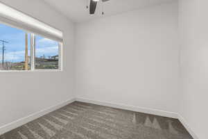 Unfurnished room featuring ceiling fan and dark colored carpet
