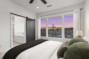Bedroom featuring a barn door, a ceiling fan, a mountain view, recessed lighting, and connected bathroom
