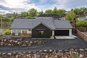 View of front of property featuring gravel driveway, brick siding, and a tiled roof