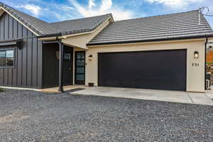 View of front of property with board and batten siding, driveway, and an attached garage