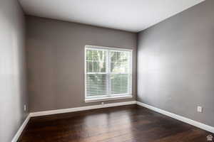 Spare room with baseboards and dark wood finished floors