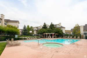 Community pool featuring a patio area, a community hot tub, and a residential view