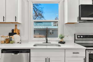 Kitchen with stainless steel appliances, white cabinetry, and light stone countertops
