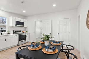 Kitchen with stainless steel range with electric cooktop, white cabinetry, light countertops, light wood-type flooring, and recessed lighting