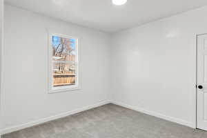 Carpeted empty room with baseboards and a textured wall