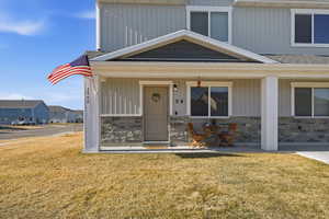 View of front of property with stone siding, a porch, and a front lawn