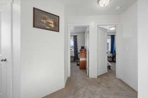 Corridor with light colored carpet and baseboards