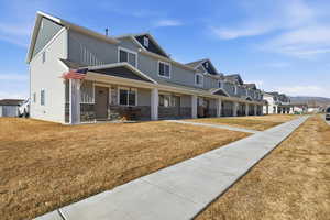 View of front of property with a porch, stone siding, a front lawn, board and batten siding, and a residential view