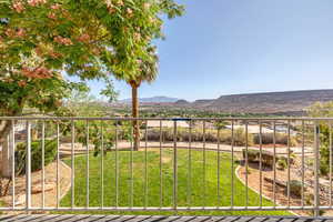View of grassy yard featuring a balcony and a mountain view