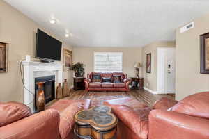 Living area with wood finished floors, a fireplace, and a textured ceiling