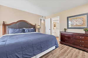 Bedroom featuring wood finished floors, connected bathroom, and a textured ceiling