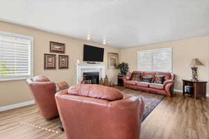 Living area featuring a tiled fireplace, light wood finished floors, and a textured ceiling