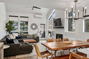 Dining space with a glass covered fireplace, suspended lighting, wood finished floors, and healthy amount of natural light