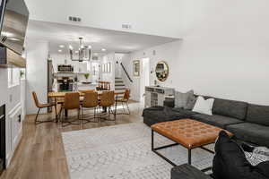 Living room featuring light wood-style floors, a chandelier, and a fireplace