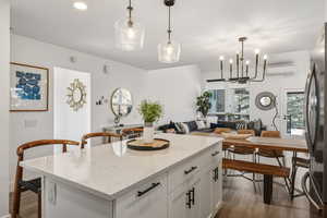Kitchen with light stone counters, open floor plan, a kitchen island, freestanding refrigerator, and dark wood finished floors