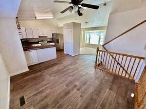 Kitchen with white cabinets, stainless steel appliances, a peninsula, dark wood-style floors, and ceiling fan