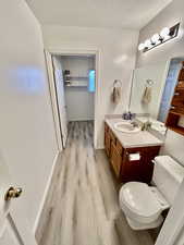 Bathroom with a textured ceiling, vanity, and light wood-style flooring