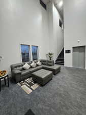 Carpeted living area with a high ceiling and elevator