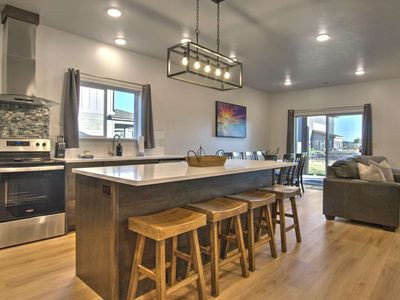 Kitchen featuring stainless steel electric range oven, light wood-style floors, light countertops, a breakfast bar, and tasteful backsplash