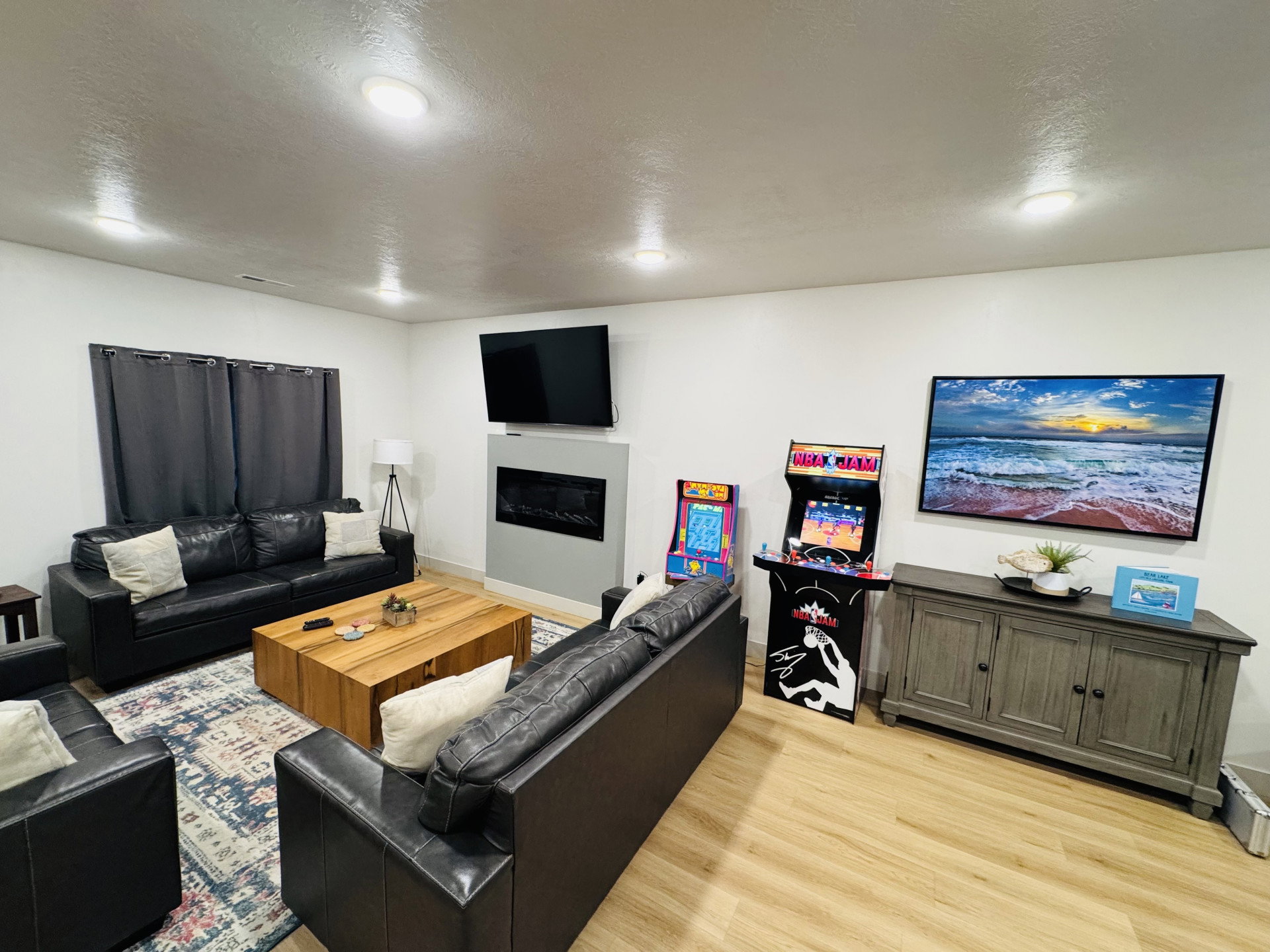 Living area featuring light wood-style flooring, a glass covered fireplace, and a textured ceiling