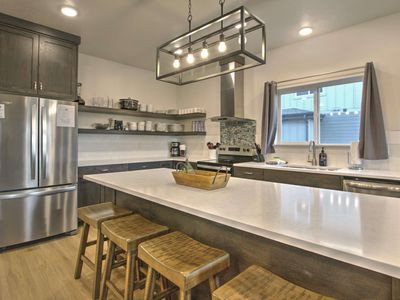 Kitchen featuring stainless steel appliances, light countertops, a breakfast bar, decorative light fixtures, and light wood-style flooring