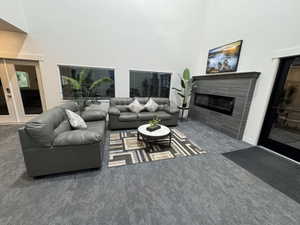 Carpeted living area with a high ceiling and a tile fireplace