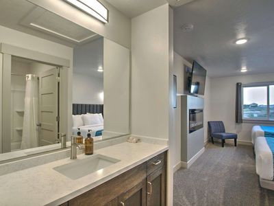 Ensuite bathroom featuring vanity, dark colored carpet, and a glass covered fireplace