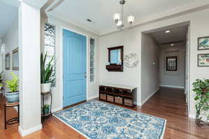 Foyer featuring suspended lighting and dark wood-type flooring