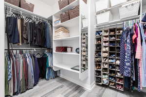 Primary walk in closet featuring light wood-style floors