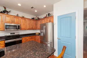 Kitchen featuring stainless steel appliances, granite countertops, wood finish cabinets, and recessed lighting
