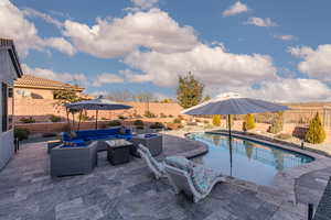 View of swimming pool with an outdoor living space, patio surround, and a fenced backyard