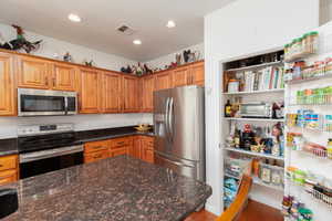 Kitchen featuring stainless steel appliances, granite countertops, wood finish cabinets, engineered wood floors, and recessed lighting