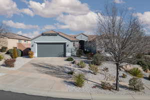 View of front of property with concrete driveway, stucco siding, an attached garage, and a tile roof