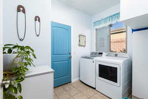 Laundry area featuring light tile patterned flooring and washer and clothes dryer