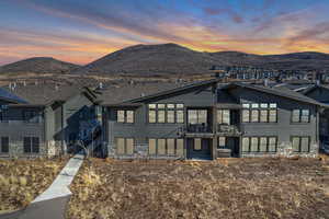 View of front of property featuring stone siding, a mountain view, and roof with shingles