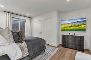 Bedroom with wood finished floors, a closet, and recessed lighting
