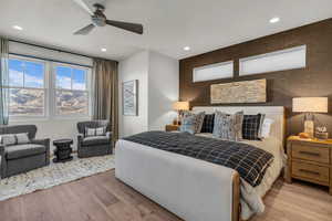 Bedroom with an accent wall, wood finished floors, recessed lighting, and a ceiling fan