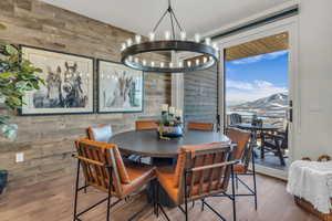 Dining room with wooden walls, a mountain view, suspended lighting, and wood finished floors