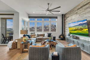 Living area featuring a wood stove, a mountain view, light wood finished floors, ceiling fan, and an accent wall