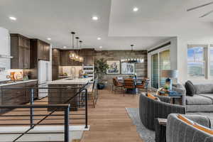 Kitchen with light wood-type flooring, an island with sink, high end fridge, dark wood finish cabinets, and a breakfast bar