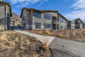 View of front of property featuring stone siding, a gate, and a balcony